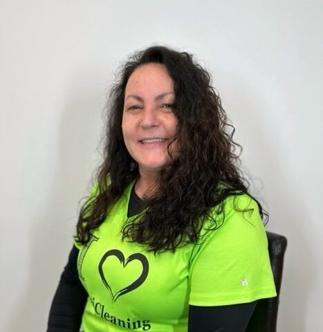 A woman wearing a green shirt with a heart on it.