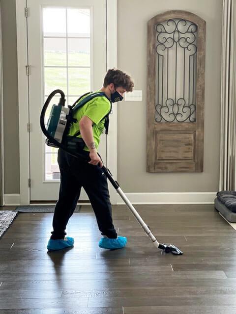 A man cleaning a hardwood floor with a vacuum.