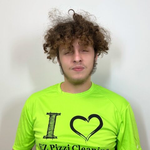 A young man wearing a green shirt with the words i love EZ Pizzi cleaning.